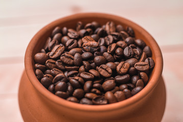Clay pot filled with coffee beans on wooden table. Menu design. Place for text or design.