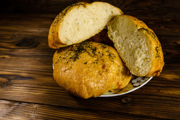 Plate with italian bun ciabatta on wooden table