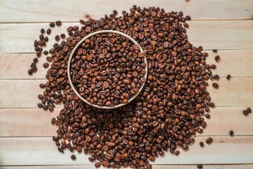 Big porcelain pot filled with coffee beans on wooden table. Place for text. Menu design. Top view.