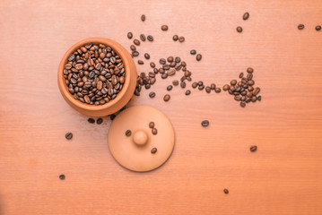 Clay pot with coffee beans on wooden table. Top view.