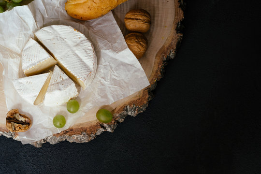 Tasting cheese dish with nuts and fruits on black table. Food for wine, cheese delicatessen. Menu design horizontal, top view.