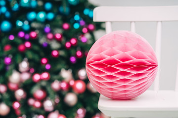 Close up pink christmas garland standing on a chair on a christmas tree backround, Copy space, Soft focus.