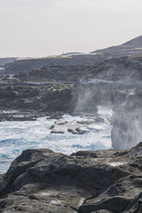  Some backlit waves break on a rock spraying.