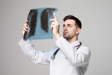 Young handsome Doctor looking at x-ray on white background
