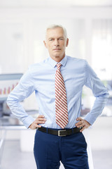 Financial business man. A senior financial consultant businessman standing in shirt and tie in his office.