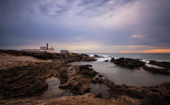 Long exposure from a lighthouse in a rocky beach in a cloudy winter day. Cascais, Portugal