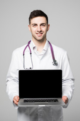 Photo of male doctor, smiling to camera and holding a laptop computer for the blank screen to add your own image of message on a white background.