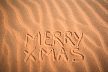 Fototapeta na wymiar Christmas greeting card: handwritten MERRY XMAS in sand background pattern.