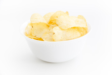 Crispy thinly sliced potato chips in white bowl, on white background.