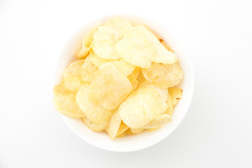 Crispy thinly sliced potato chips in white bowl, on white background.