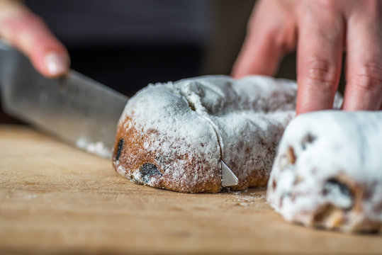 Closeup Female Hands Cutting Mini Marzipan Stollen with Knife on Wooden Board