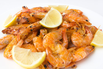 Fried prawns on a white plate. Shrimp fried in oil with garlic and lemon on a plate.