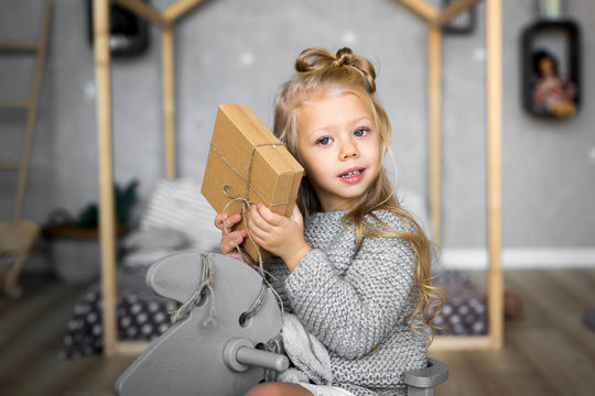 Merry Christmas and Happy Holidays. Cheerful cute child girl opening a Christmas present.