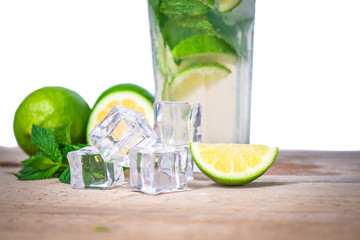 Mojito cocktail with fresh lime, mint leaves and ice cubes in a transparent glass on a wooden background. Refreshing alcohol drink. Isolated on white background.