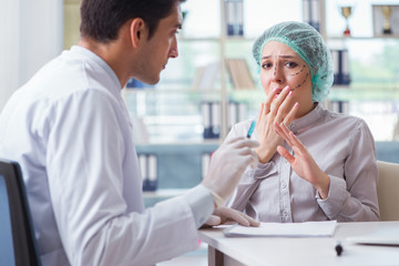 Plastic surgeon preparing for operation on woman face