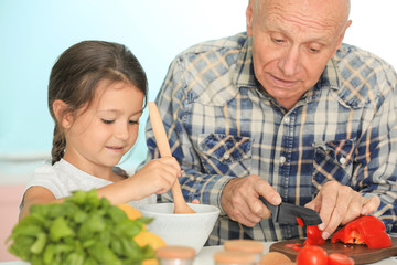 Senior man cooking together with his granddaughter on kitchen