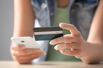 Young woman with credit card and mobile phone, closeup