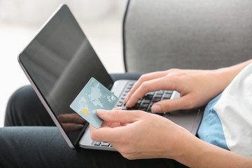 Young woman with credit card working on laptop, closeup