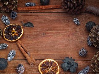 Wooden background with pinecones, cinnamon and tangerines. Top view.