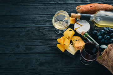A bottle of wine, grapes and cheese on a wooden background. Cheese brie, blue cheese, gorgonzola, fuete, salami. Italian Traditional Cuisine. Free space for text. Top view.