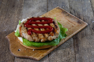 Roll with roast cutlet. Hamburger on a wooden board. Kitchen table,