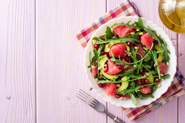 Fresh salad with arugula, grapefruit, avocado, pomegranate seeds and pine nuts.