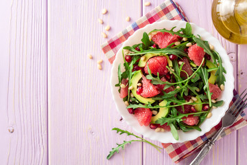 Fresh salad with arugula, grapefruit, avocado, pomegranate seeds and pine nuts.