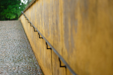 The old handrail along the wall. Old rusty handrail and mounting along stony natural wall. Hiking Trail Guide Rod pavers