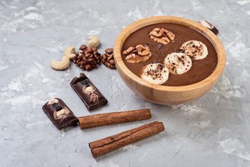 Chocolate smoothie on a bowl with banana and nuts on grey stone  background