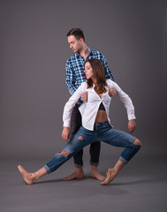 Couple of ballet dancers posing over gray background in casual clothes