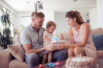 Boy opening gift with parents and surprise.