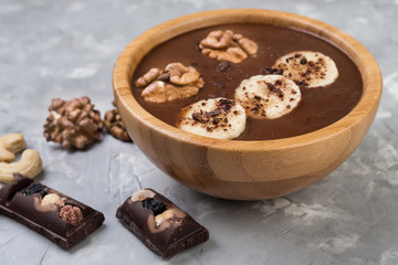 Chocolate smoothie on a bowl with banana and nuts on grey stone  background