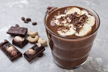 Chocolate smoothie with banana and nuts on grey stone  background