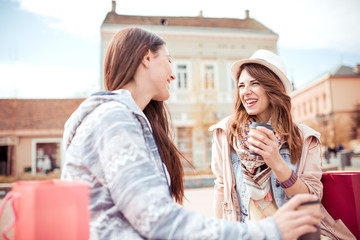 Beautiful young girls in the city drinking coffee to go.