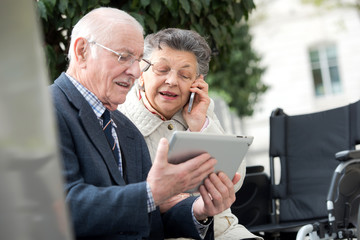 senior couple holding tablet and giving a call