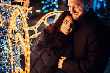 Happy couple in love with christmas lights behind