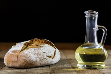 Obraz premium Tasty country bread and olive oil in a glass bottle. Wooden table.