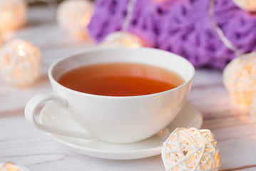Cup of black tea, plaid, and Christmas garlands glow