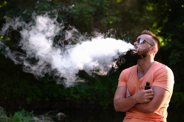 Men with beard smoke electronic cigarette outdoor