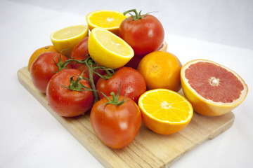 Tomato and orange on the white background with green leafs on th