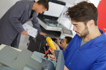 young man measuring voltage in service center