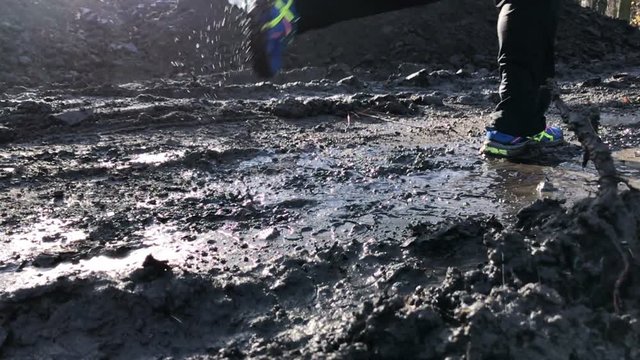 Close-up of man's feet running in the mud.
