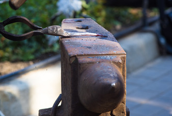 blacksmith performs the forging of hot glowing metal on the anvil