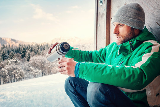 Man drinks a hot drink worker ot traveler on open winter air