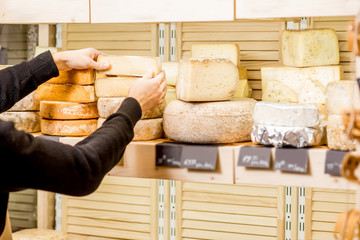 Cheese seller putting goods on the shelves at the cheese store