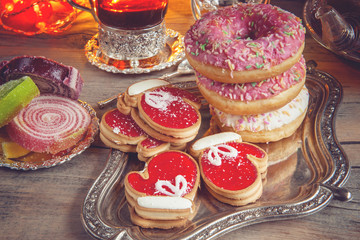 Colorful Christmas donuts and cookies on a wooden table in a rustic, cosy style.