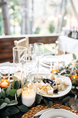 Decorated table with gold plates, candles and greens on the white tablecloth