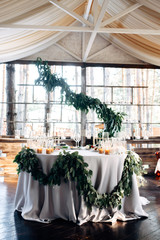 Decorated table for two with gold plates, candles and greens on the white tablecloth