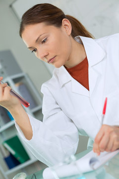 woman researcher is surrounded by medical vials and flasks