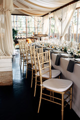 Decorated table with gold plates, candles and greens on the white tablecloth